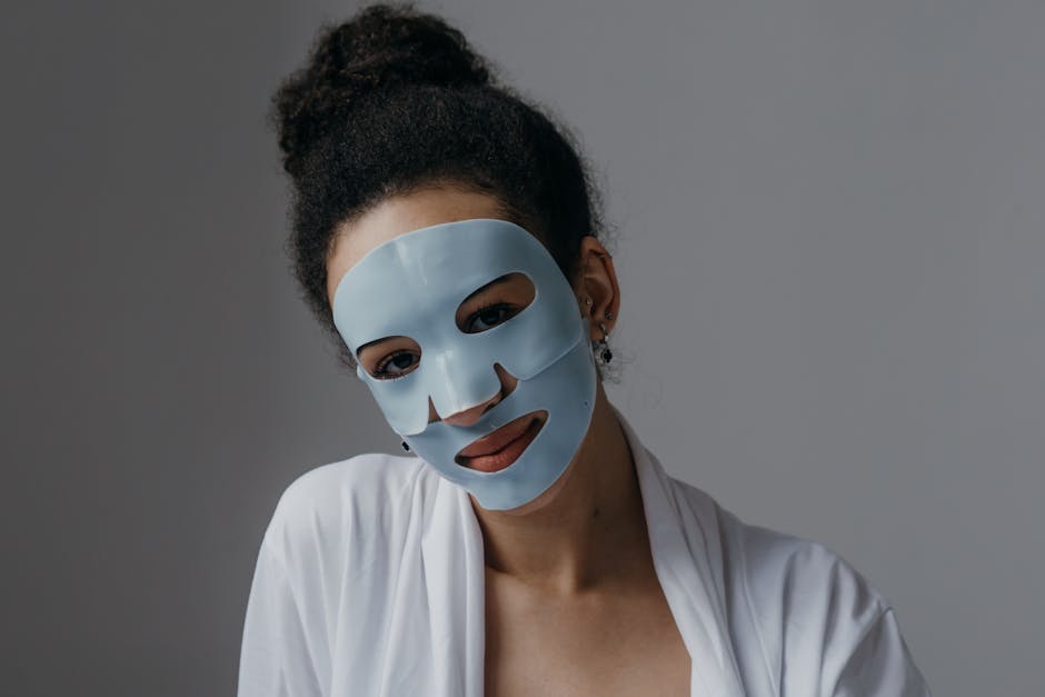 Adult woman enjoying a skincare routine with a blue sheet mask indoors.