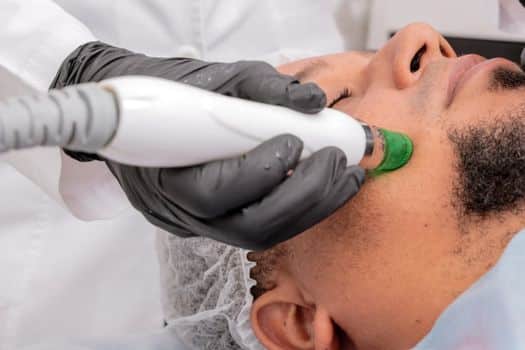 A close-up of a man receiving a professional skincare treatment in a clinical setting.